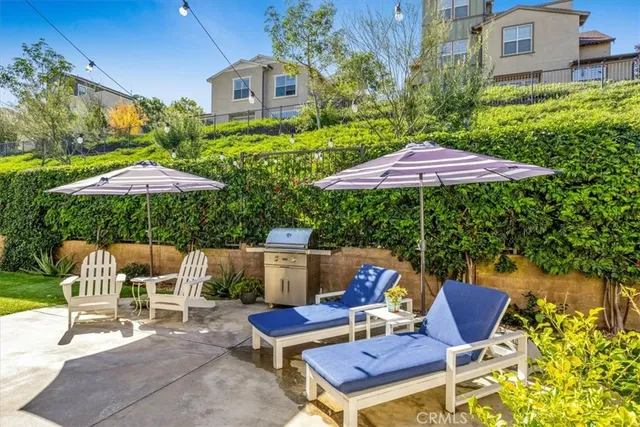 a backyard of a house with table and chairs under an umbrella
