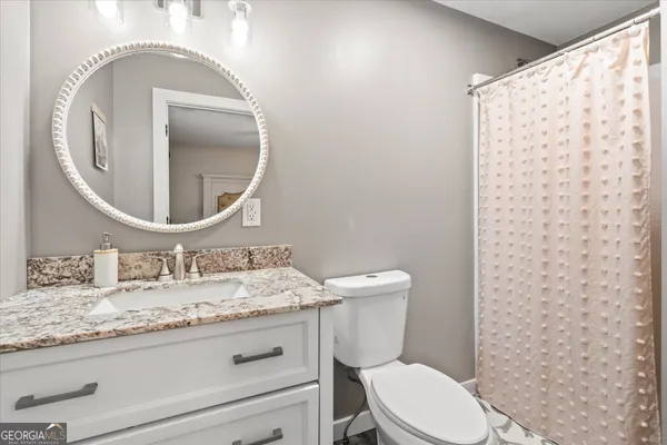 a bathroom with a granite countertop toilet mirror vanity and a sink