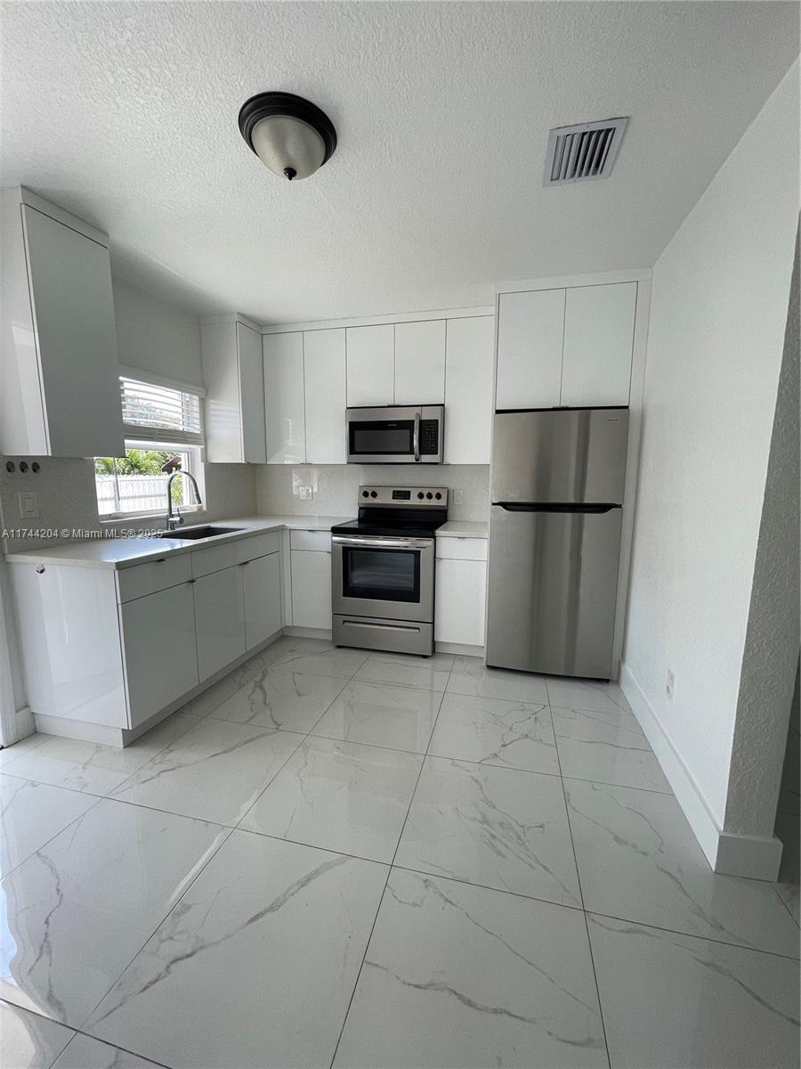 5155 Northwest 12th Avenue Miami, FL 33127 - Photo 4 of 18 a kitchen with granite countertop a refrigerator and a stove top oven