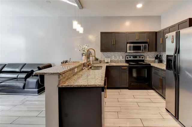a kitchen with stainless steel appliances granite countertop a sink stove and refrigerator