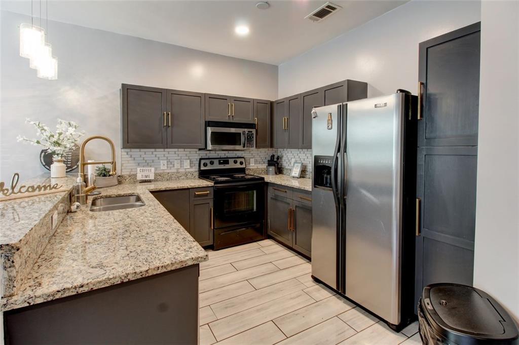 870 Mayson Turner Road Northwest, Unit 1102 Atlanta, GA 30314 - Photo 2 of 27 a kitchen with kitchen island granite countertop stainless steel appliances a sink a stove and a refrigerator