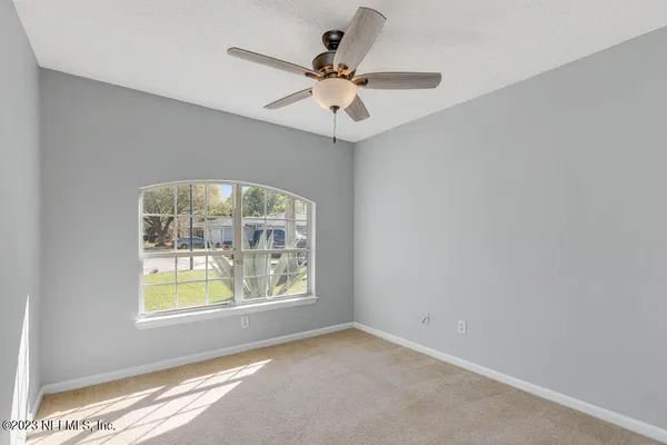 an empty room with windows and ceiling fan