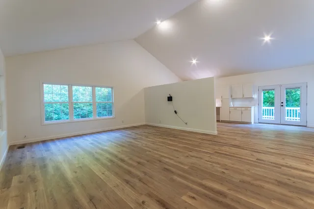 an empty room with wooden floor and windows