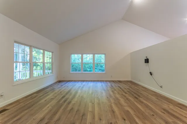 an empty room with wooden floor and windows