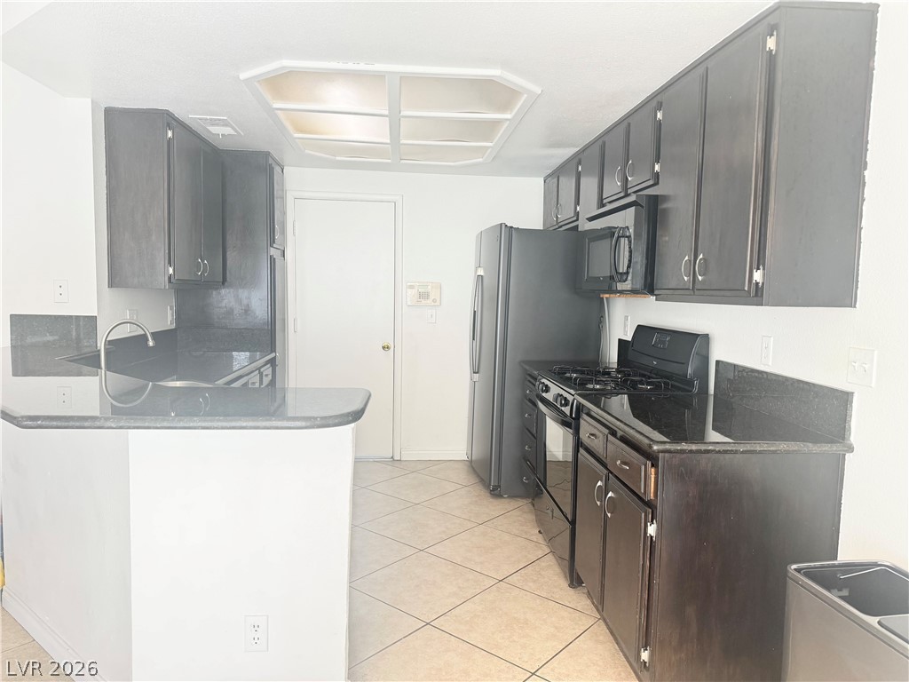 135 Primero Way Henderson, NV 89074 - Photo 7 of 15 A functional kitchen features dark cabinetry, contrasting countertops, and a full suite of appliances.