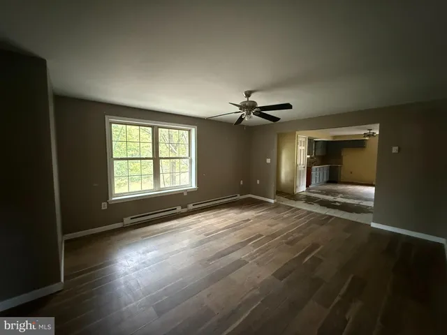 an empty room with wooden floor chandelier fan and windows