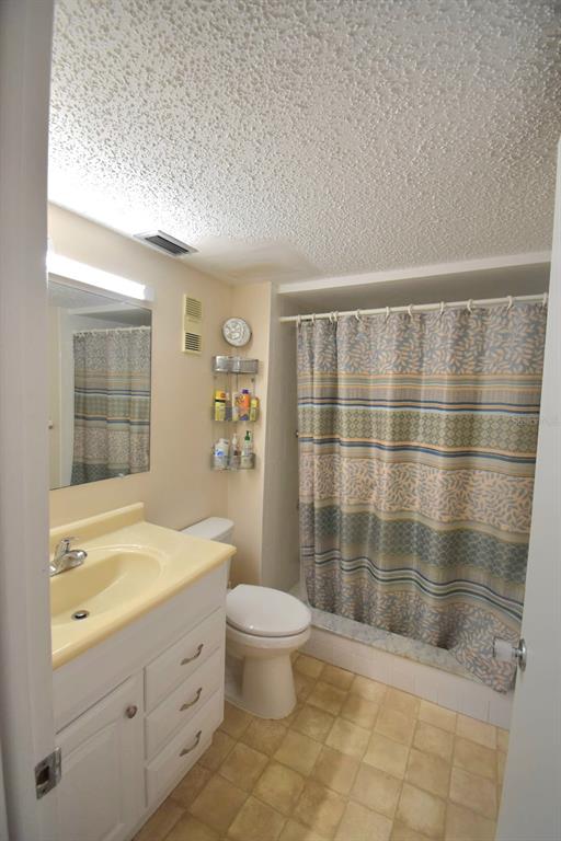936 Virginia Street, Unit 206 Dunedin, FL 34698 - Photo 8 of 22 a bathroom with a granite countertop sink a toilet a mirror and shower