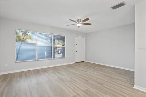 a view of an empty room with a window and wooden floor