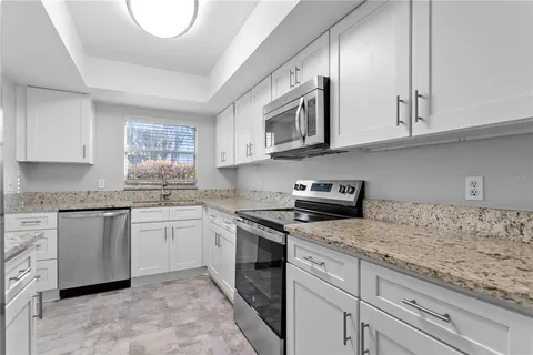 a kitchen with granite countertop white cabinets and stainless steel appliances