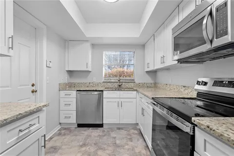 a kitchen with granite countertop cabinets stainless steel appliances and a sink