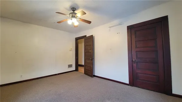 an empty room with closet and a chandelier fan