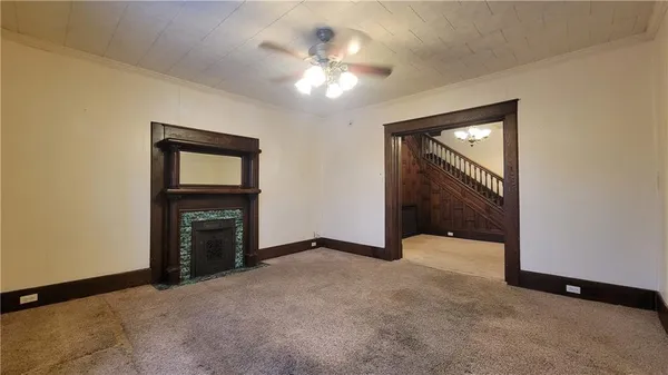 a view of an empty room with a fireplace and a ceiling fan