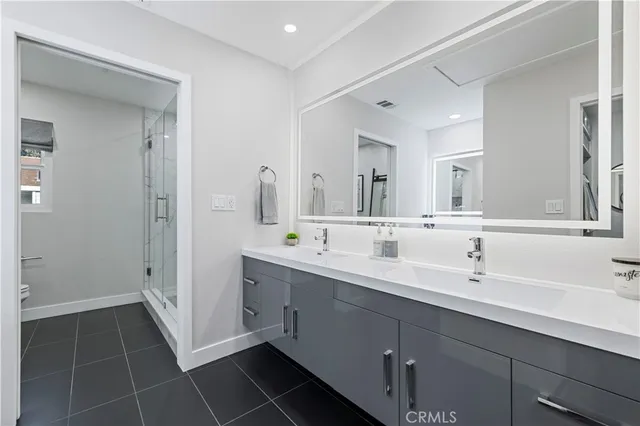 a spacious bathroom with a double vanity sink a toilet and a mirror