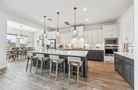 a kitchen with stainless steel appliances kitchen island granite countertop a table chairs sink and cabinets