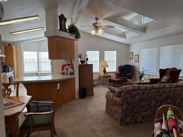 a living room with furniture a chandelier fan and a window