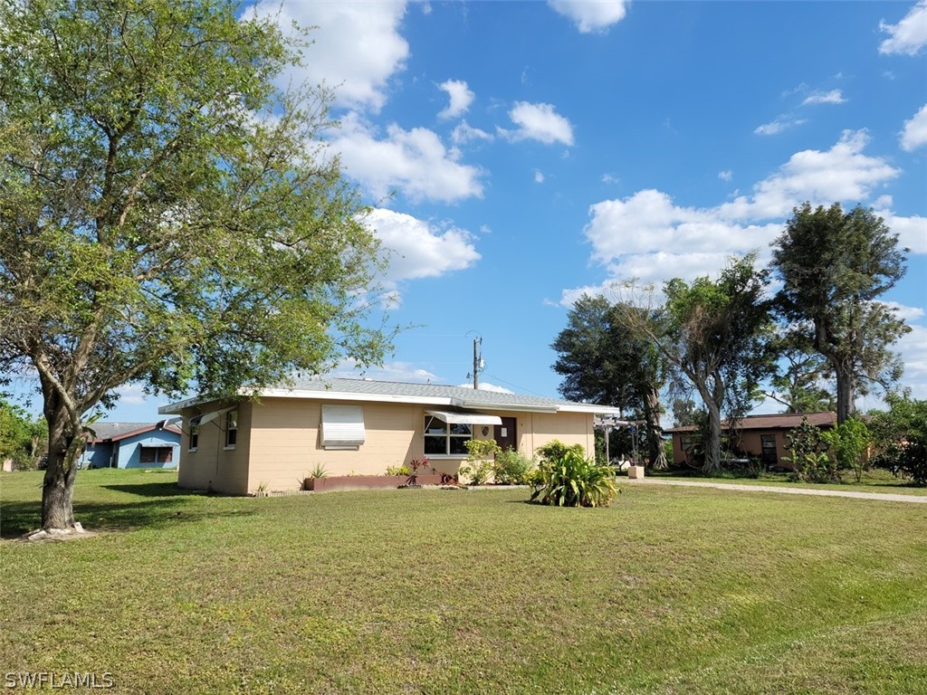 114 Florida Road Lehigh Acres, FL 33936 - Photo 1 of 12 a front view of a house with a garden