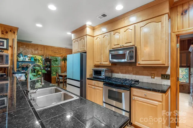a kitchen with stainless steel appliances granite countertop a sink a stove and a microwave