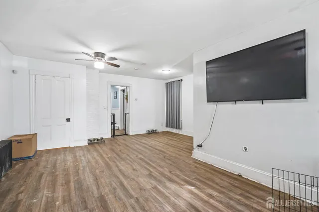 a view of a livingroom with wooden floor and a flat screen tv