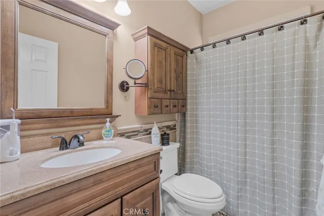 a bathroom with a granite countertop sink toilet a mirror and shower curtain