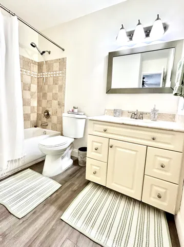 a bathroom with a double vanity sink a toilet a mirror and shower