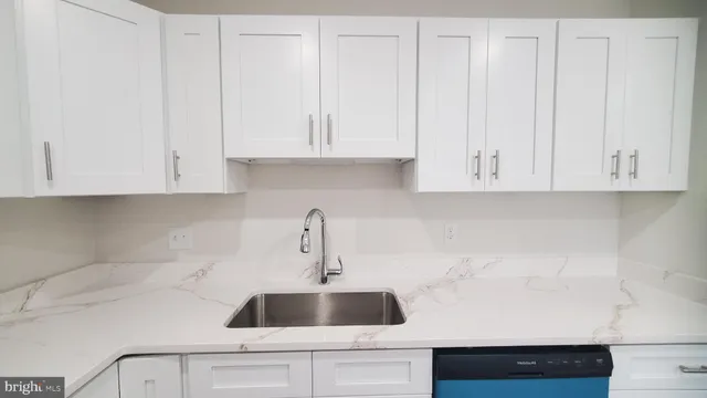 a kitchen with white cabinets and sink