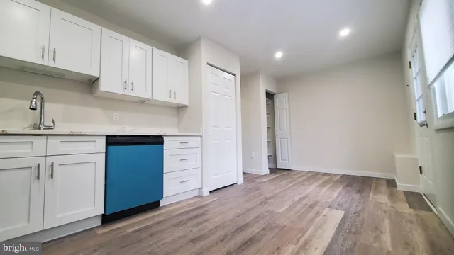 a kitchen with granite countertop a sink cabinets and wooden floor