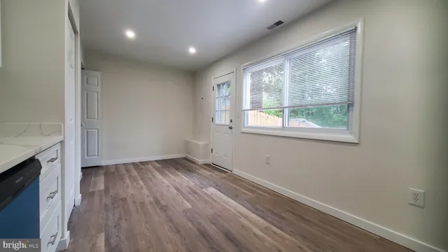 an empty room with wooden floor and windows