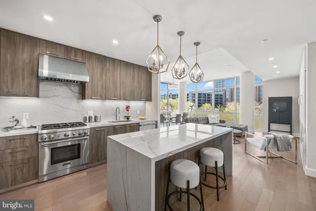 a kitchen with stainless steel appliances granite countertop a stove a sink a oven a dining table and chairs with wooden floor