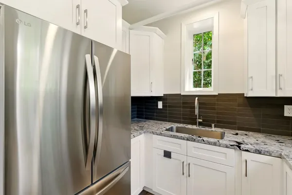 a kitchen with granite countertop white cabinets and refrigerator