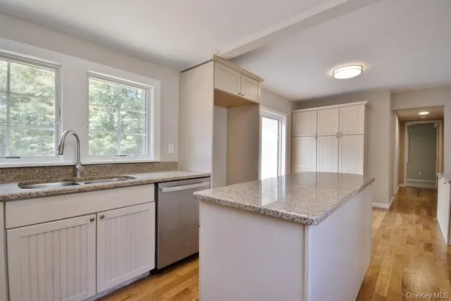 a kitchen with granite countertop kitchen island with white cabinets and wooden floor