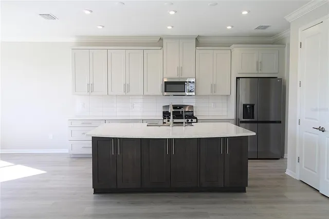 a kitchen with kitchen island a sink stainless steel appliances and cabinets