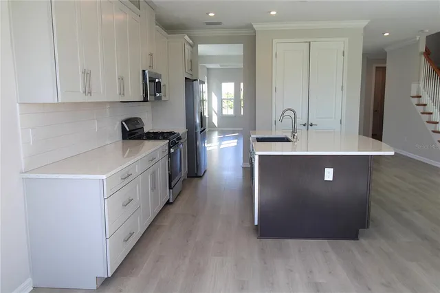 a kitchen with stainless steel appliances granite countertop a sink a stove and refrigerator