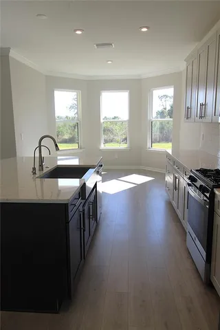 a kitchen with stainless steel appliances a sink dishwasher a stove a refrigerator white cabinets and wooden floor