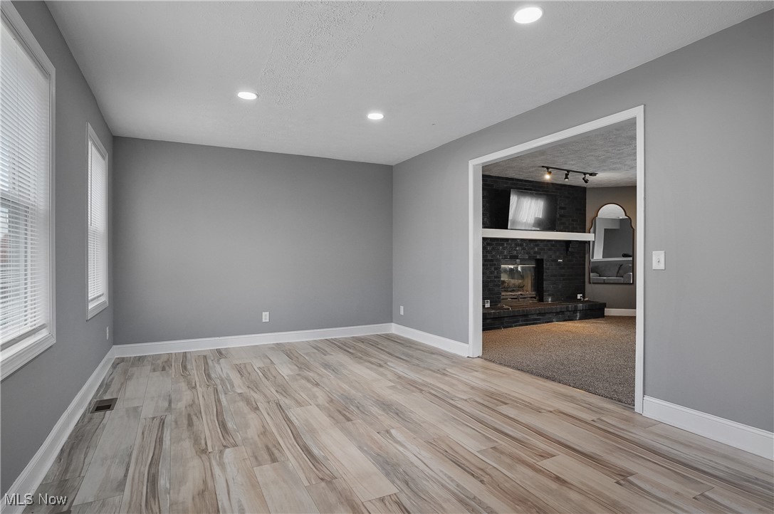 9278 Bryant Road Windham, OH 44288 - Photo 10 of 47 Spare room with a textured ceiling, light wood finished floors, a fireplace, recessed lighting, and rail lighting
