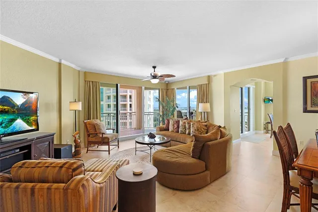 a living room with furniture a flat screen tv and large windows