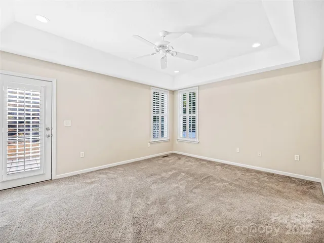 an empty room with windows and ceiling fan
