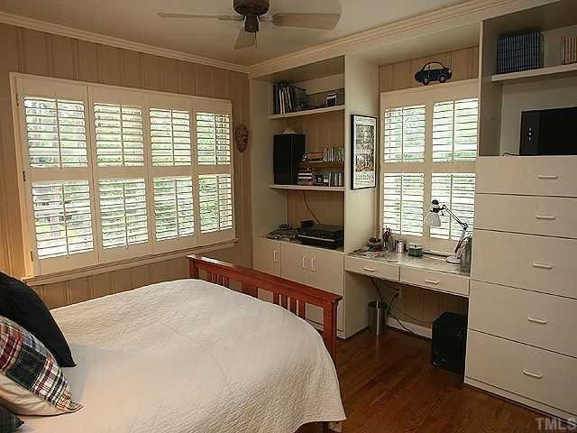 2605 Wells Avenue Raleigh, NC 27608 - Photo 10 of 12 Secondary bedroom with hardwoods, ceiling fan, built-in bookcases, desk and dresser. Windows are already dressed with nice wood plantation shutters. Bedroom