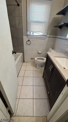 a bathroom with a granite countertop sink toilet and washing machine
