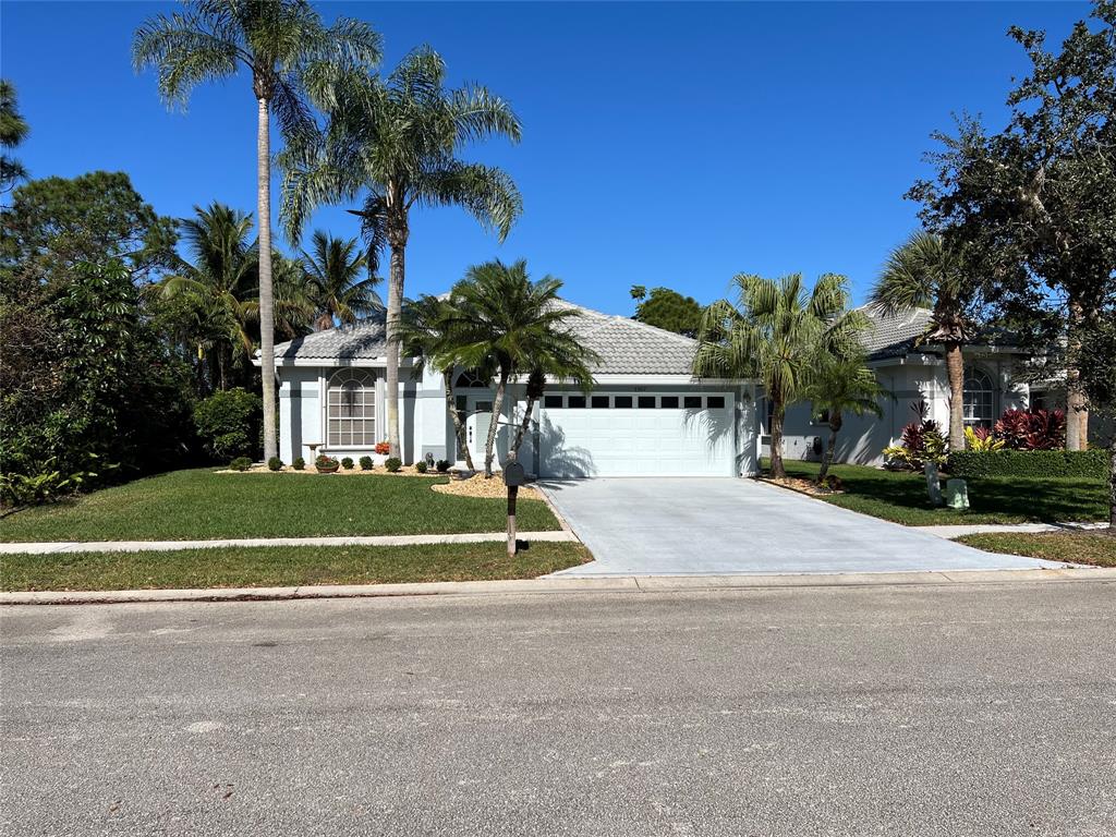7352 Southeast Seagate Lane Stuart, FL 34997 - Photo 1 of 19 a front view of a house with a yard and palm trees