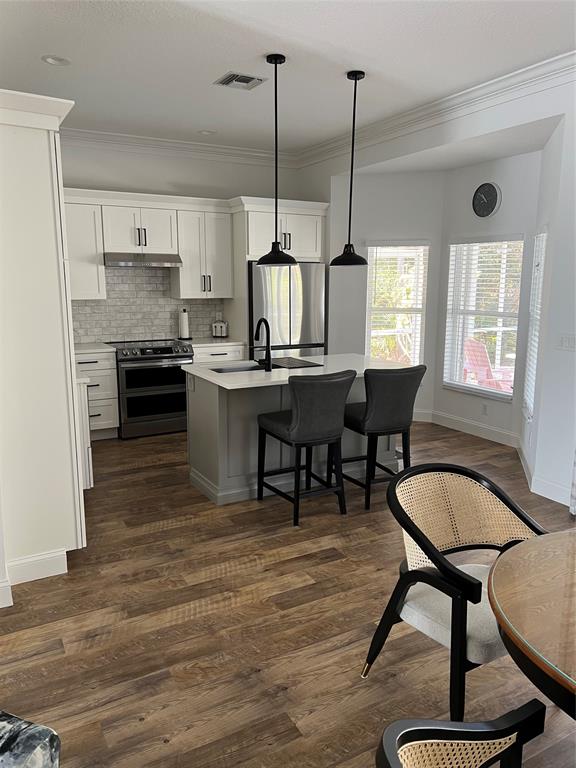 7352 Southeast Seagate Lane Stuart, FL 34997 - Photo 7 of 19 a kitchen with stainless steel appliances granite countertop a stove kitchen island a table and chairs in it