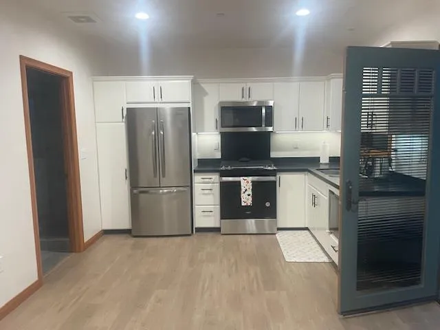 a kitchen with stainless steel appliances granite countertop a refrigerator a stove and a sink