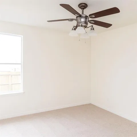 an empty room with a window and a fan