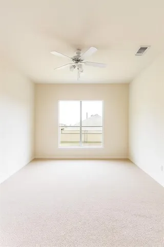 an empty room with chandelier fan and windows