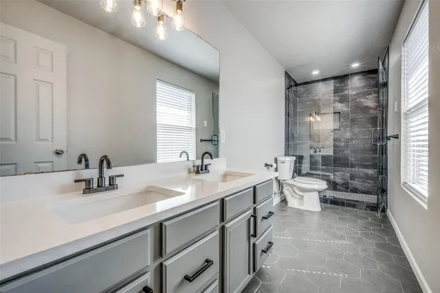 a bathroom with a double vanity sink toilet mirror and bathtub