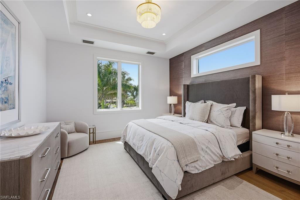 529 Neapolitan Way Naples, FL 34103 - Photo 19 of 26 a bedroom with a bed and a chandelier