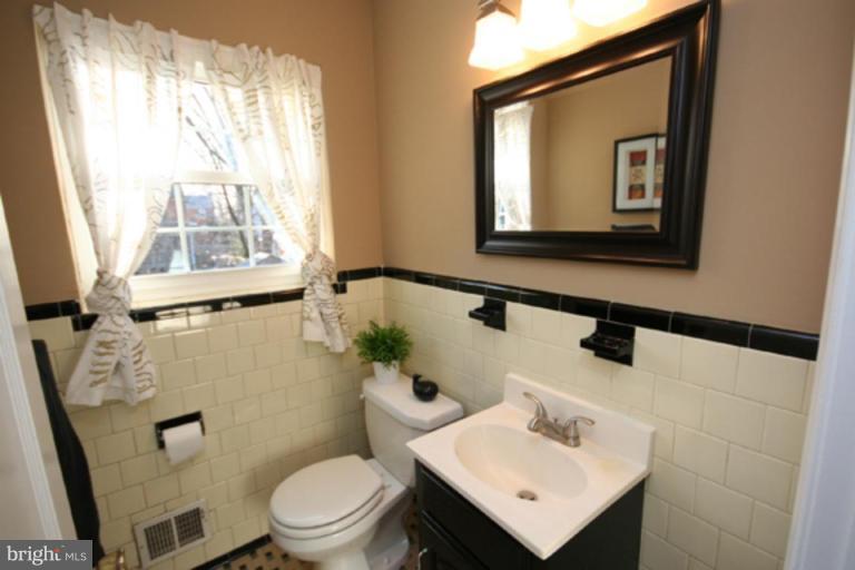 9106 Bradford Road Silver Spring, MD 20901 - Photo 13 of 18 a bathroom with a toilet sink and mirror