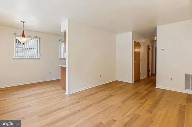 a view of an empty room with window and wooden floor