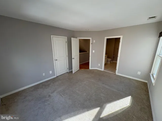 a view of an empty room with closet and a window