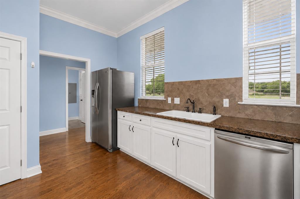 179 Ranchtown Road Elm Grove, LA 71051 - Photo 5 of 26 Kitchenette featuring wood-finish flooring, white cabinetry with dark hardware, a white undermount sink with a dark faucet, and a stainless steel dishwasher