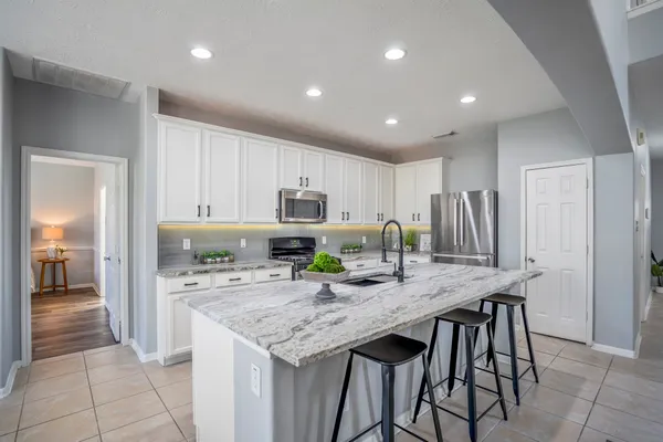 a kitchen with stainless steel appliances granite countertop a table chairs and refrigerator